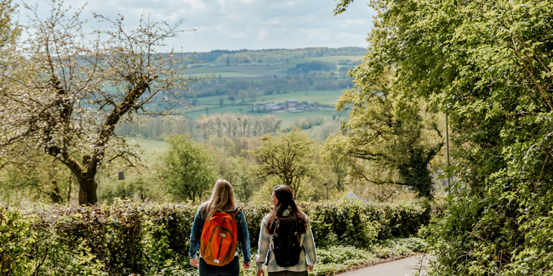 Twee sportieve vrouwen wandelen door heuvellandschap op een mooie lentedag
