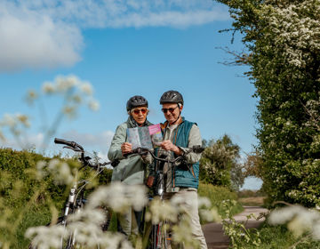 Echtpaar bekijkt routeboekje tijdens een fietstocht langs bloesem.