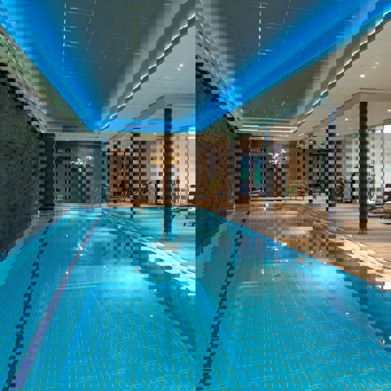 binnenzwembad in wellness met ligstoeltjes aan de zijkant. 