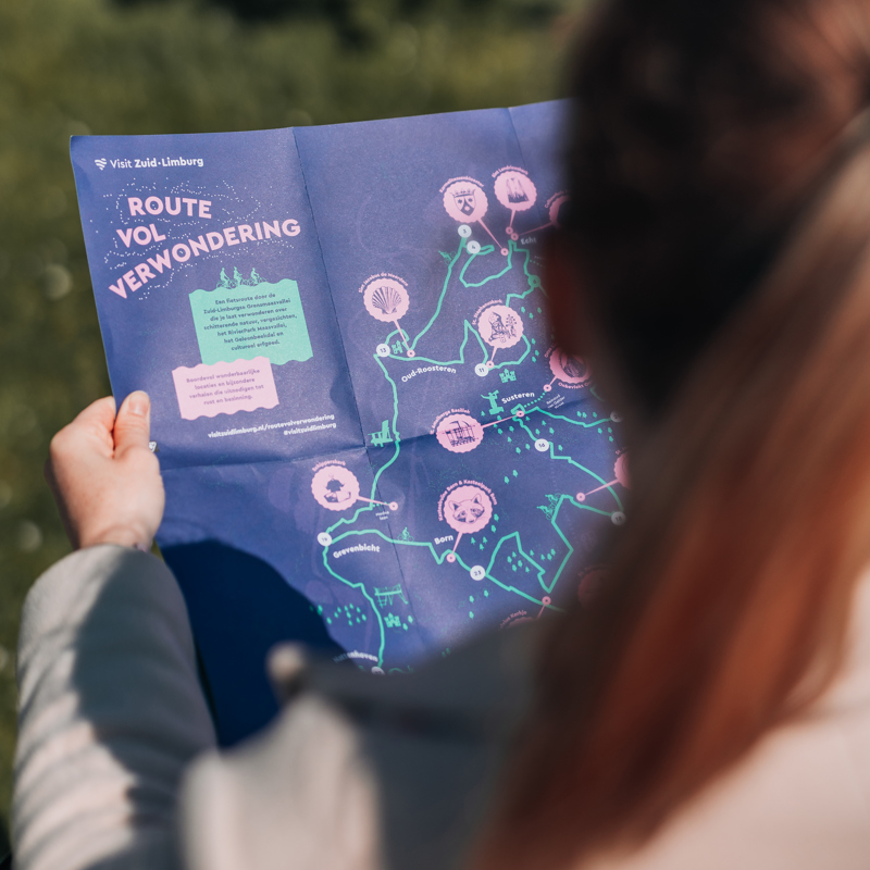 Dame opent de fietskaart met informatie over de route vol verwondering. 