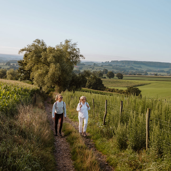 Twee dames wandelen over een wandelpad in Epen met panorama op de achtergrond