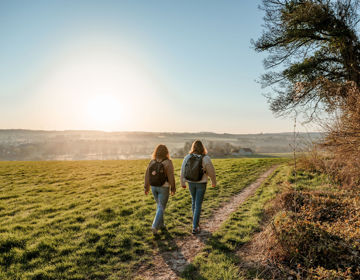 Twee wandelaars wandelen over een wandelpad bij zonsopkomst rondom de Gulperberg