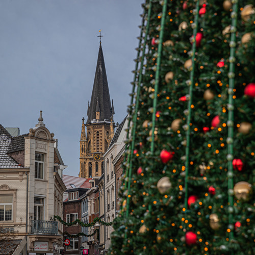 Doorkijkje van kerstboom op Markt Sittard naar kerktoren
